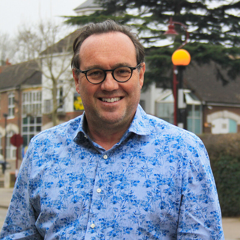 Photo of Stuart Howard, Fundraising Officer for the Hertsmere Lib Dems, smiling while standing on Radlett High Street.